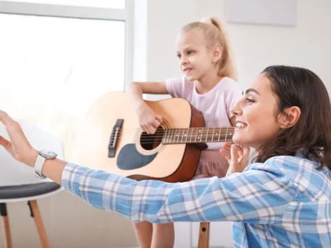 a person playing a guitar with a girl sitting on a chair