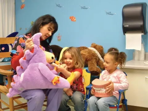 a person and several children sitting on a couch with a teddy bear