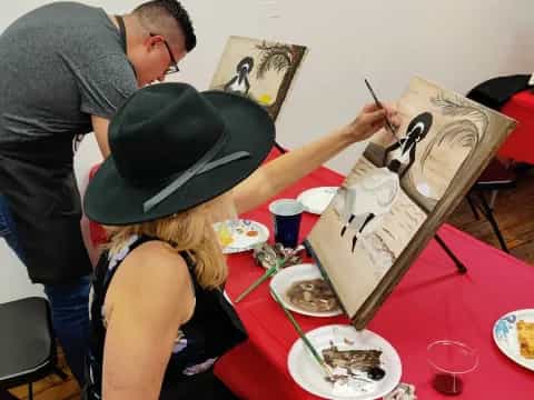 a woman in a hat painting a picture of a man