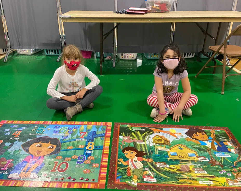 a couple of children sitting on the floor with a table and chairs