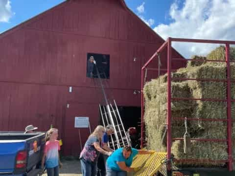 a group of people standing next to a red barn