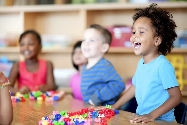 a group of children sitting at a table with a cake