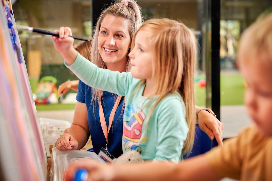 a person helping a young girl with a toothbrush