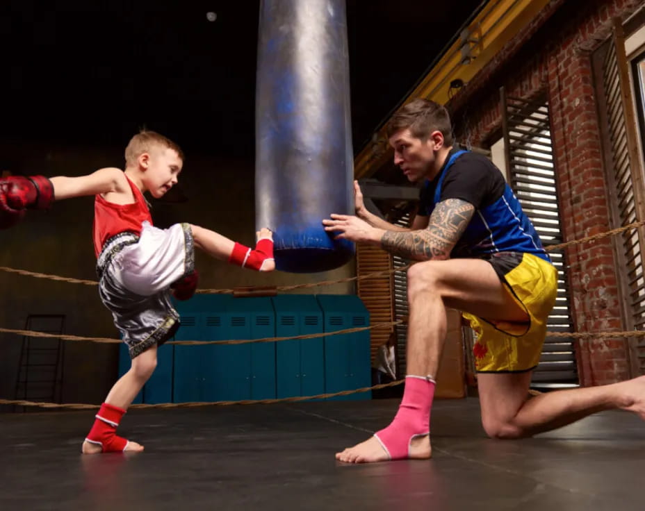 a person and a boy in boxing gloves in a gym