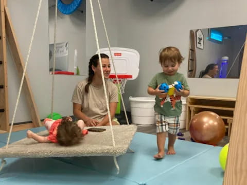 a person and a couple children playing with a ball in a playroom