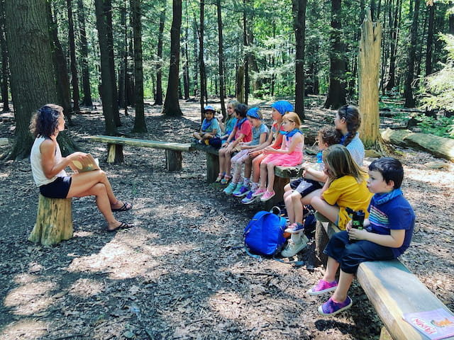 a group of people sitting on a bench in the woods