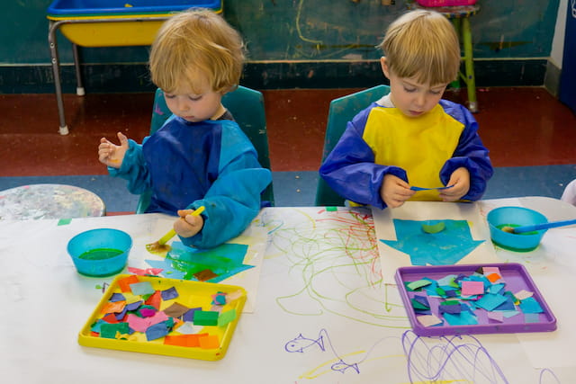 a couple of kids sitting at a table with art