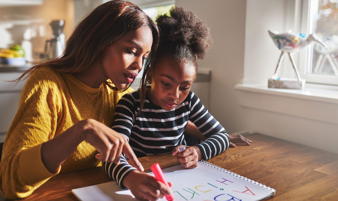 a woman and a child drawing on a paper