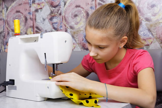 a young girl using a sewing machine