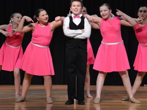 a person standing in front of a group of girls in pink dresses