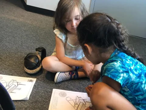 a couple of children looking at a drawing on the floor