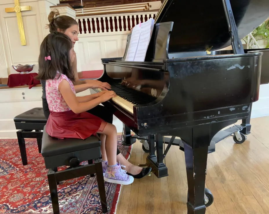 a couple of girls playing piano