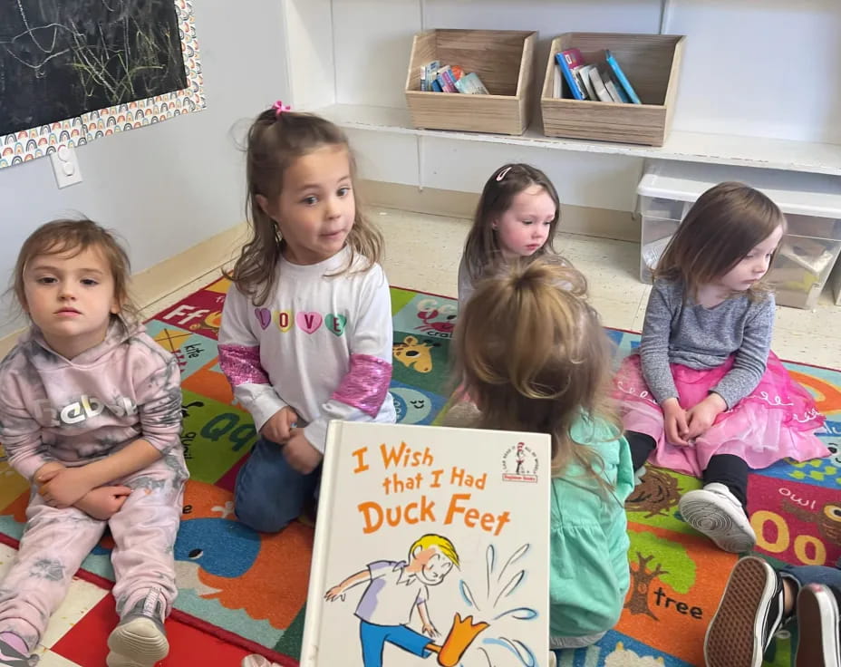 a group of children sitting on a bed holding a sign