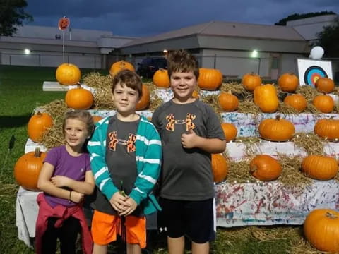 a group of kids posing for a picture in front of pumpkins