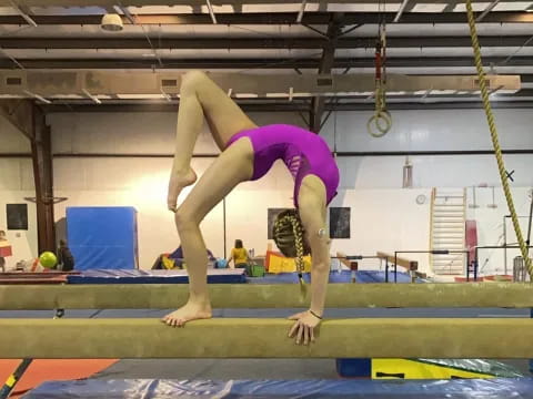 a woman doing a handstand on a mat in a gym
