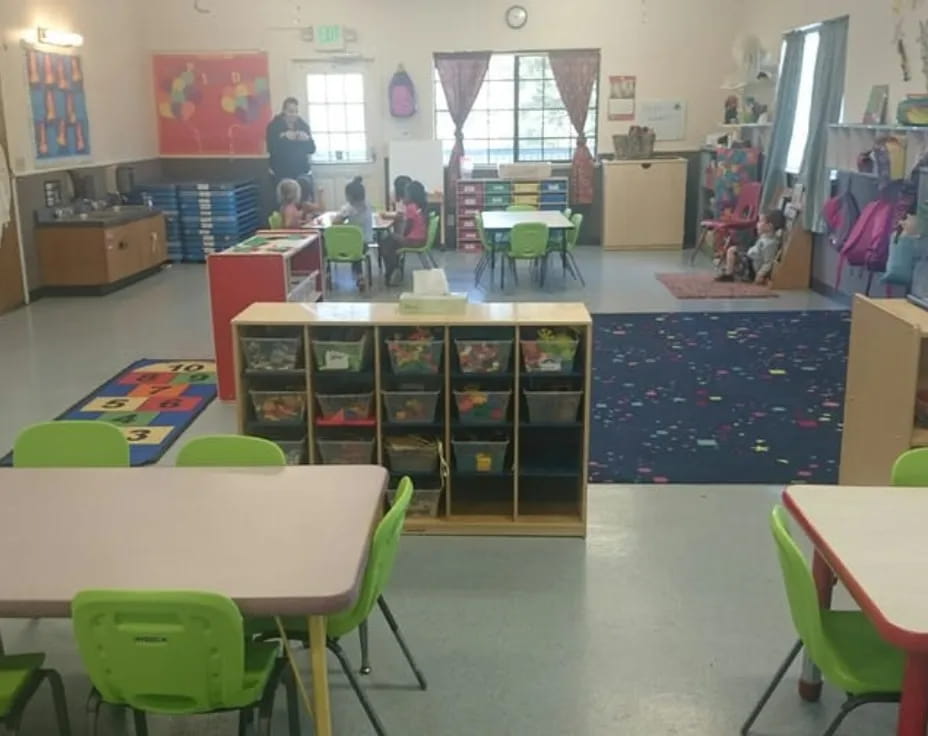 a classroom with green chairs and tables