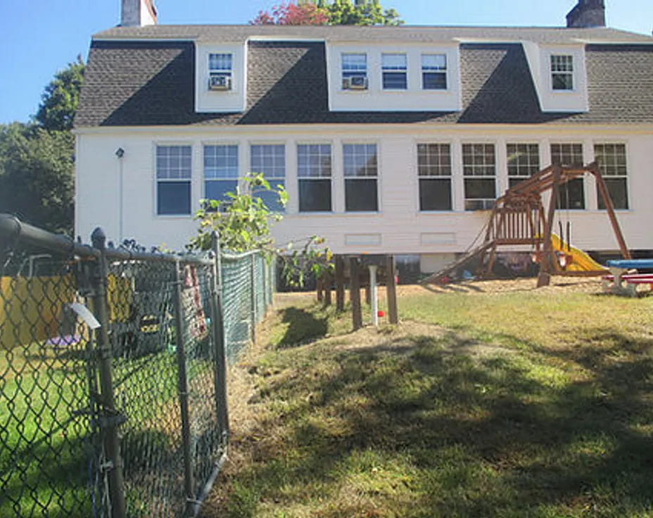 a house with a fence and a yard with a swing set
