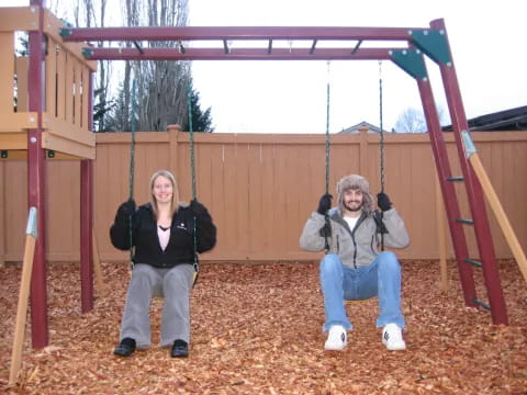 a man and woman sitting on a swing set