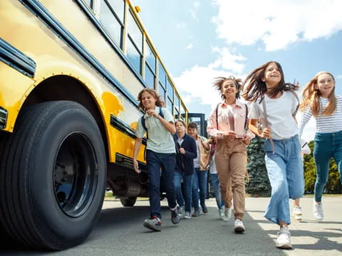 a group of people standing next to a yellow school bus