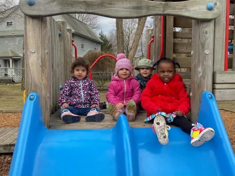 a group of children sitting on a blue slide