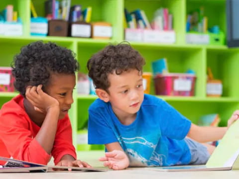 a couple of children sitting at a table looking at a book