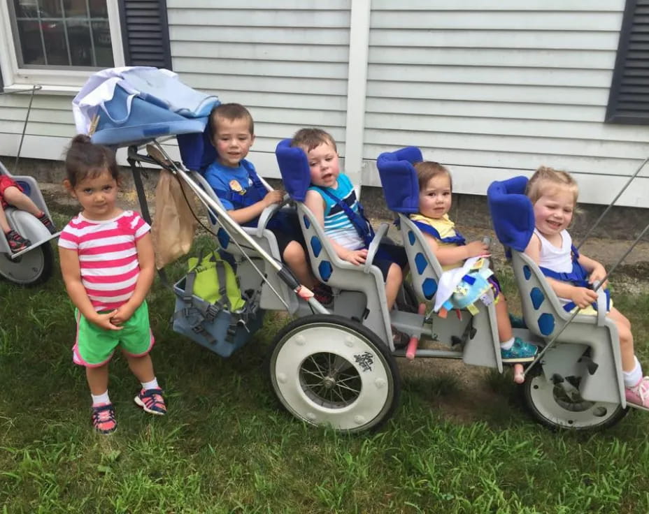 a group of kids sitting in lawn chairs in front of a house
