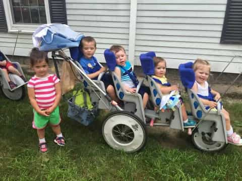 a group of kids sitting in lawn chairs in front of a house