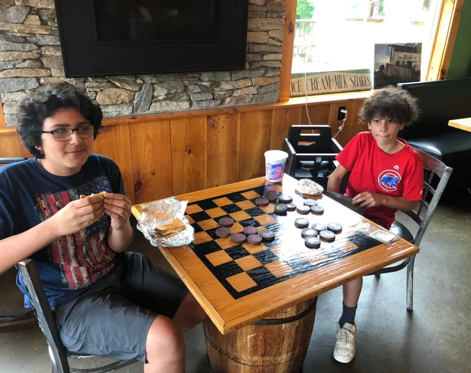 a person and a boy sitting at a table with a board game