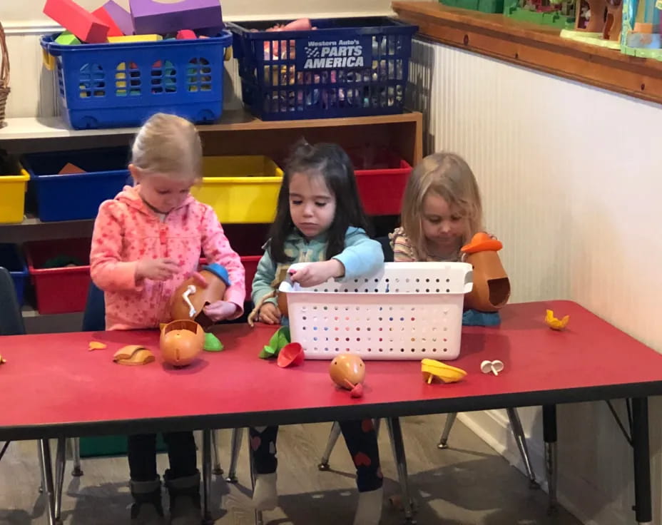 a group of children sitting at a table with baskets and baskets