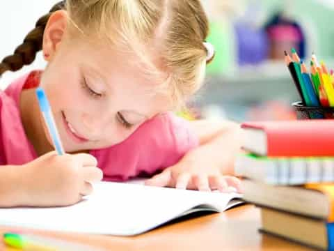 a young girl writing on a book