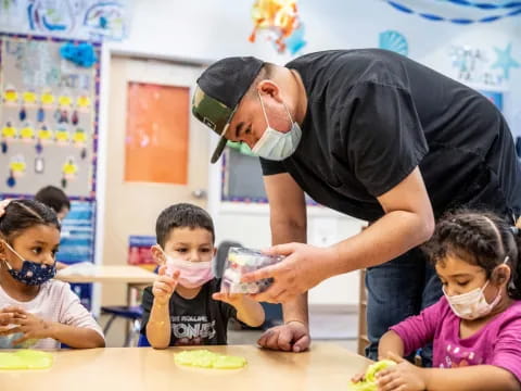 a person teaching children how to use a microscope