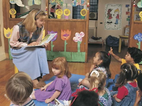 a person reading a book to a group of children