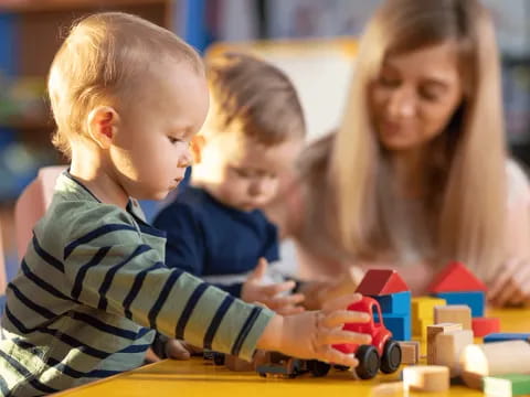 a person and a couple of children playing with building blocks