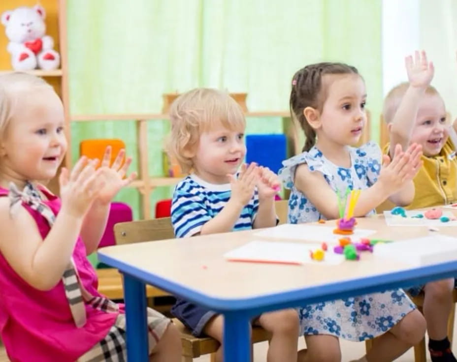 a group of children sitting at a table with a cake