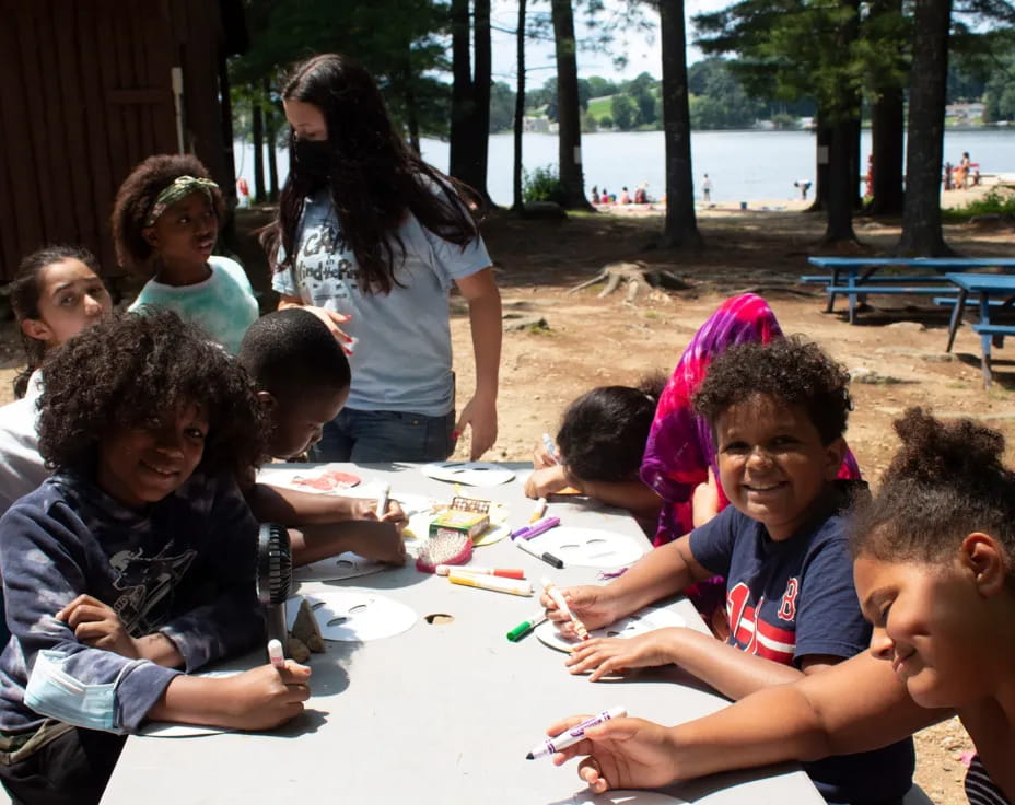 a group of children sitting at a table outside