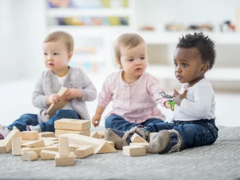 a group of babies playing with blocks