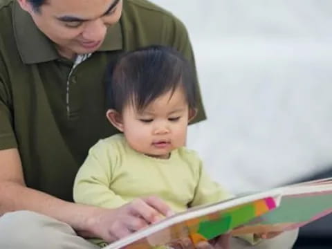 a person reading a book to a baby