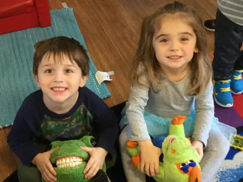 a boy and girl sitting on the floor with toys