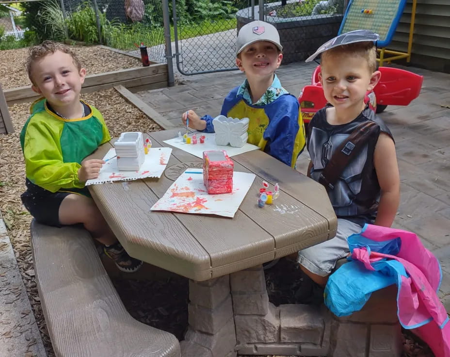 a group of kids sitting at a table outside