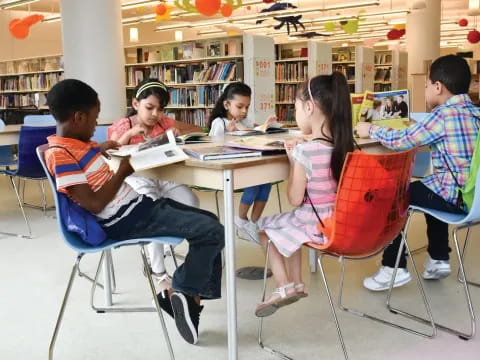 a group of children sitting at a table in a library