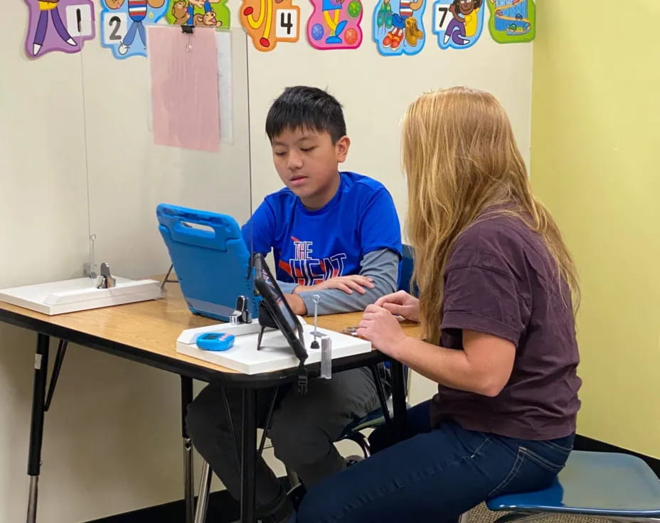 a boy and girl sitting at a table with a laptop