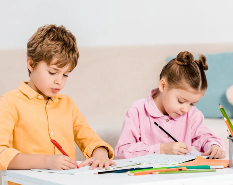 a couple of children sitting at a table looking at a book