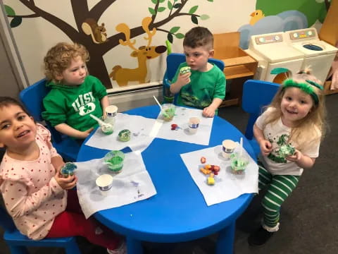 a group of children sitting at a table with food and drinks