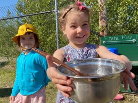 a couple of girls holding a pot of water