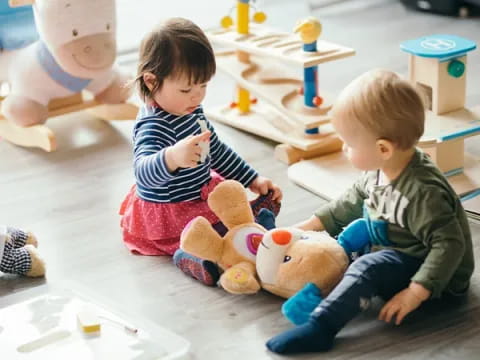 a couple of children sitting on the floor with stuffed animals