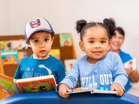 a couple of young children sitting at a table with books