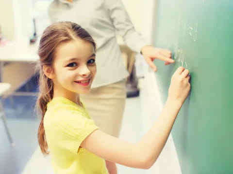 a girl writing on a chalkboard