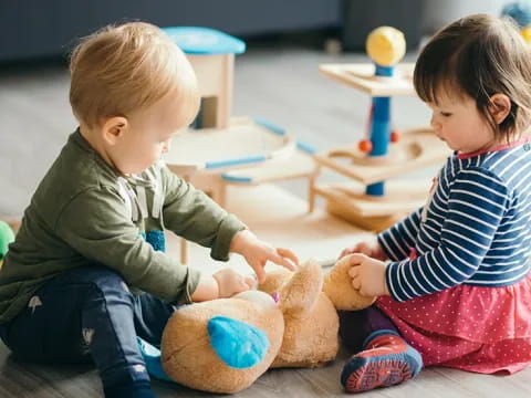 a couple of children playing with a stuffed animal