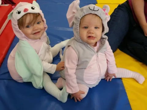 two babies sitting on a yellow blanket