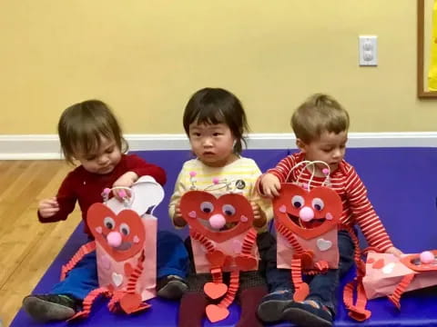 a group of children sitting on a blue mat with stuffed animals